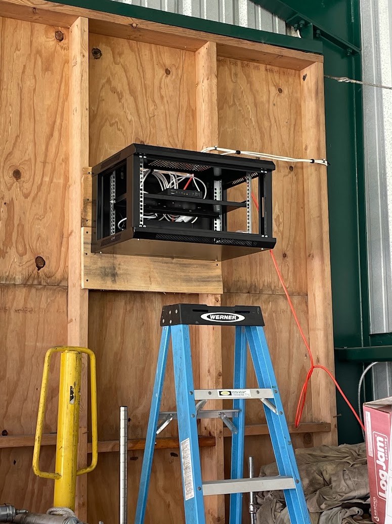 Outdoor wall-mounted network enclosure installed in a warehouse or barn setting